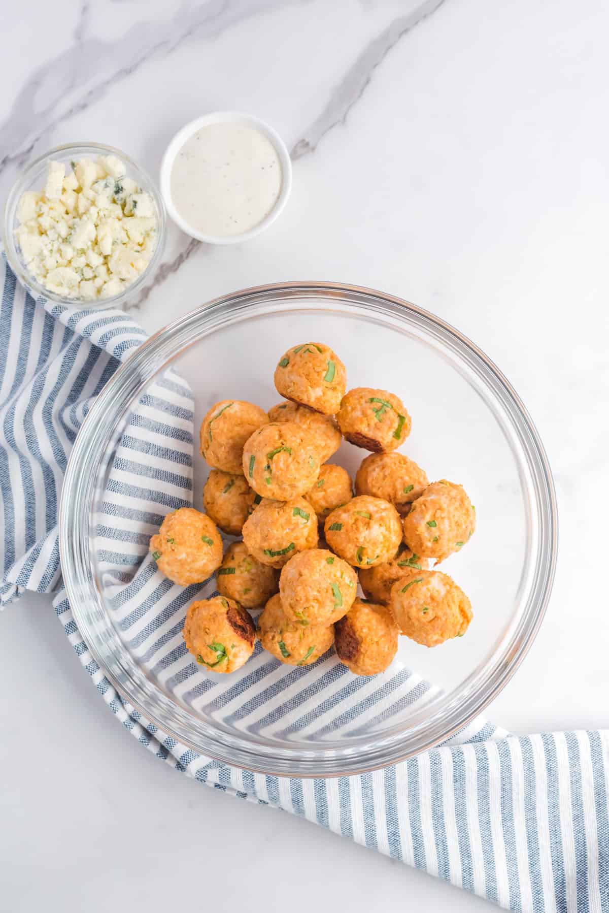 Cooked chicken meatballs in a glass mixing bowl.