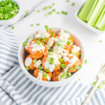 Overhead photo chicken meatballs in a white bowl topped with ranch dressing, blue cheese crumbles and diced green onions.
