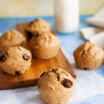 A close-up shot of a freshly baked chocolate chip muffin, with extra muffins behind it.