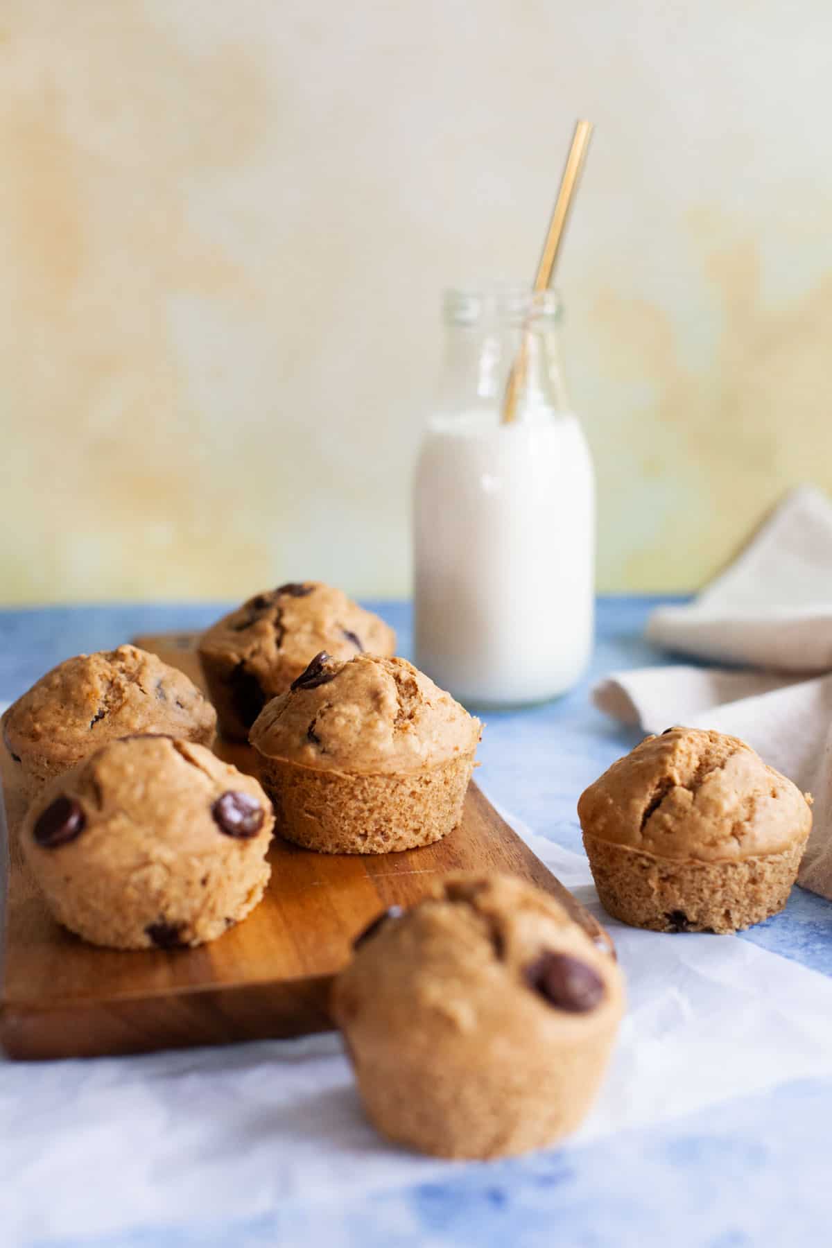 Chocolate chip muffins and milk on a countertop.