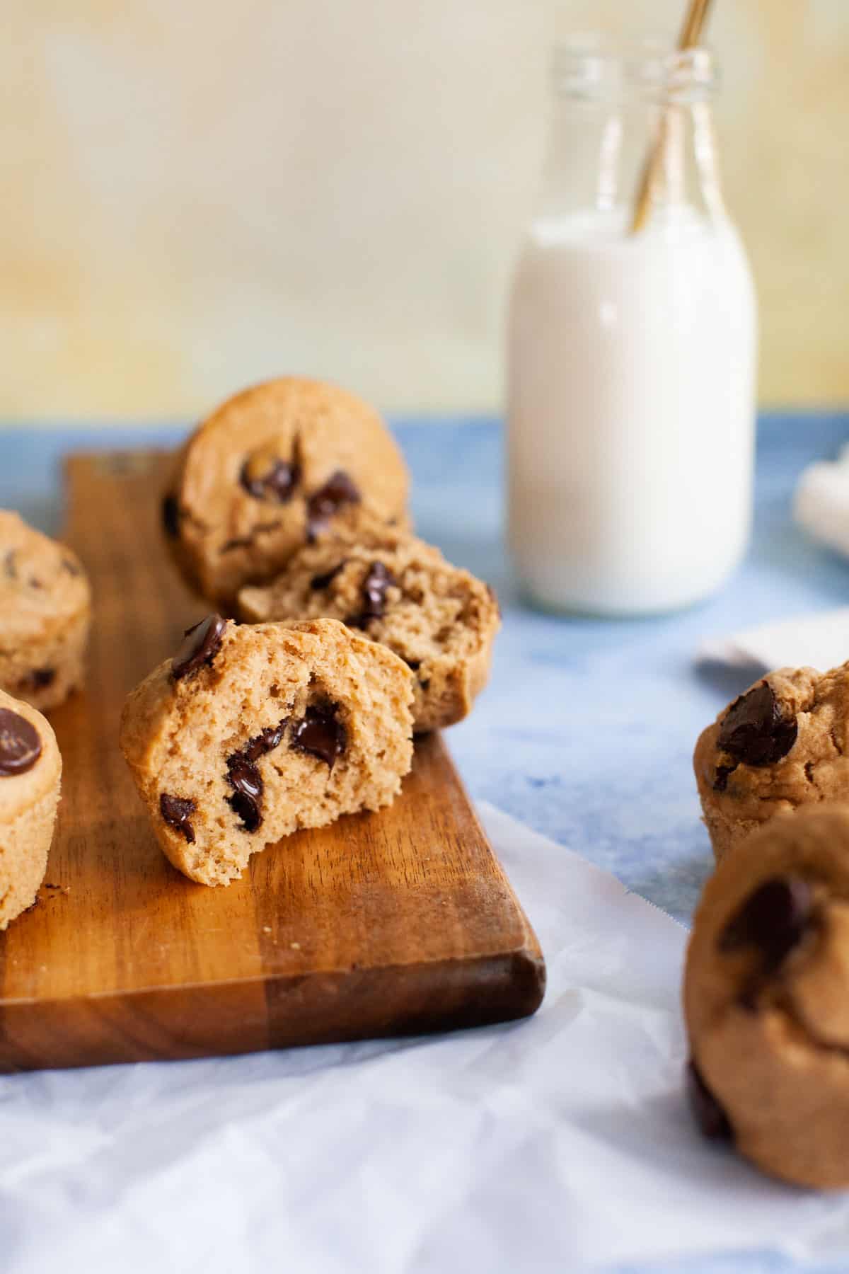 A chocolate chip muffin, cut in half, sitting on a cutting board.