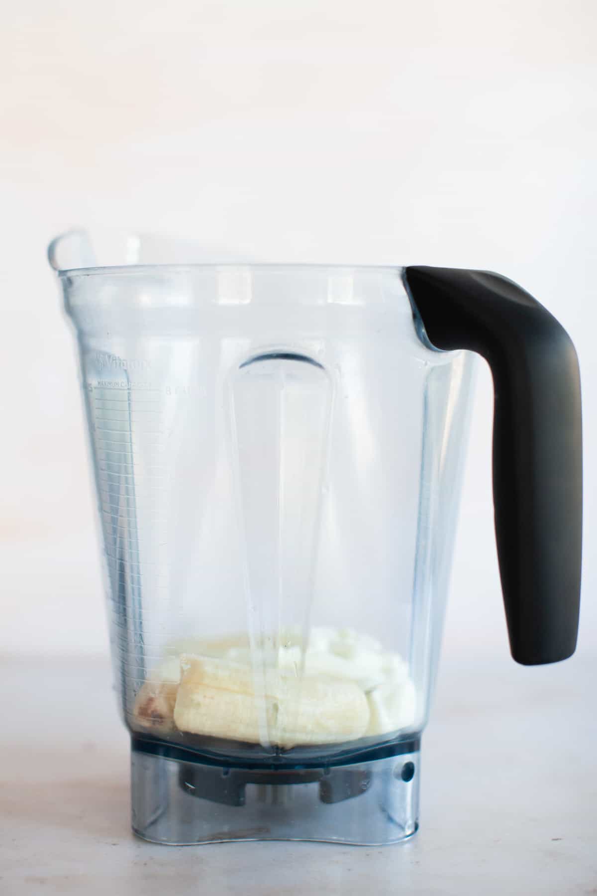 Frozen banana and plain Greek yogurt in a blender pitcher.