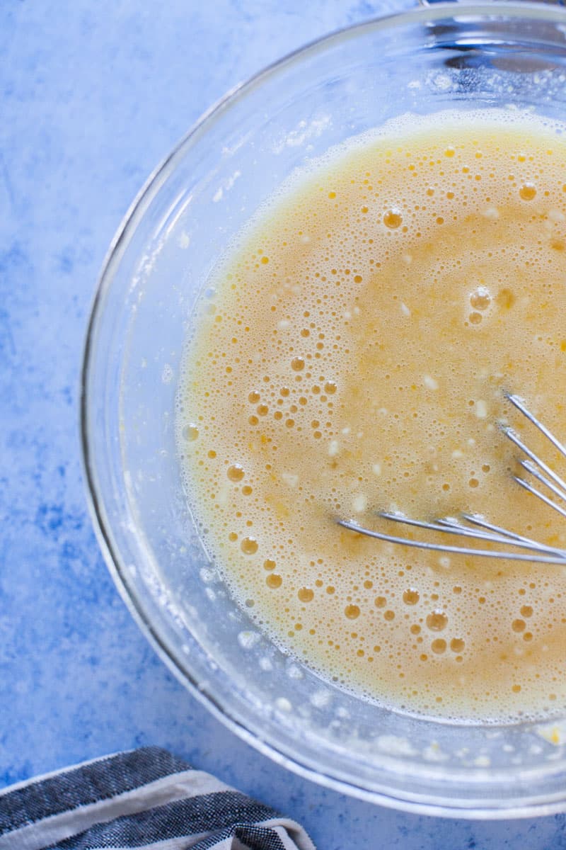 Egg, sugar and flour completely mixed in glass mixing bowl.