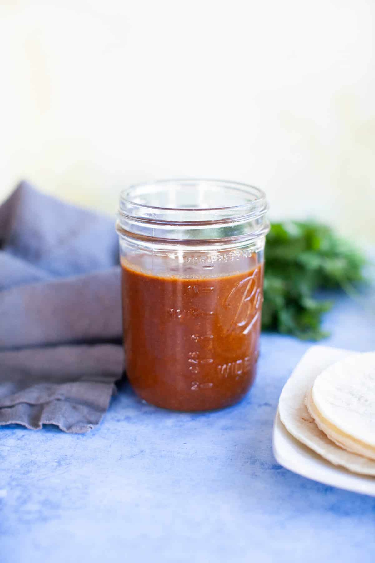 Side shot of enchilada sauce in a glass mason jar.