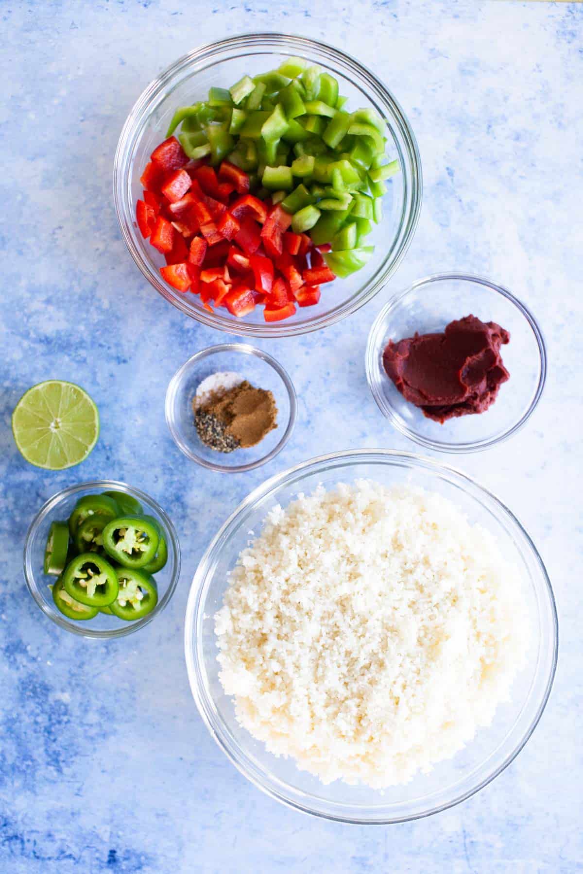 Mexican cauliflower rice ingredients separated in individual glass bowls.