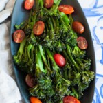 An overhead shot of roasted broccolini garnished with sliced cherry tomatoes.