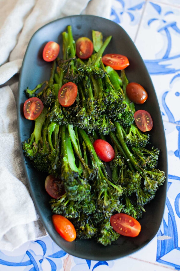 An overhead shot of roasted broccolini garnished with sliced cherry tomatoes.