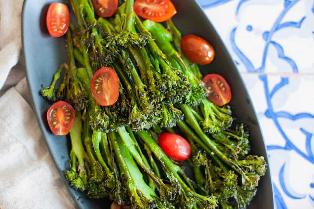 tomatoes and broccolini on a black plate.
