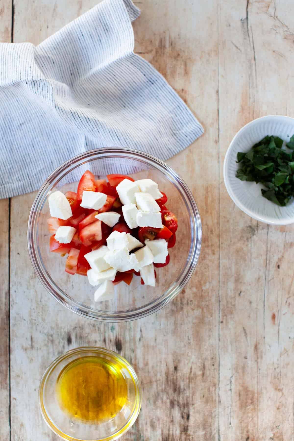 Ingredients for bruschetta pizza toppings in separate bowls.