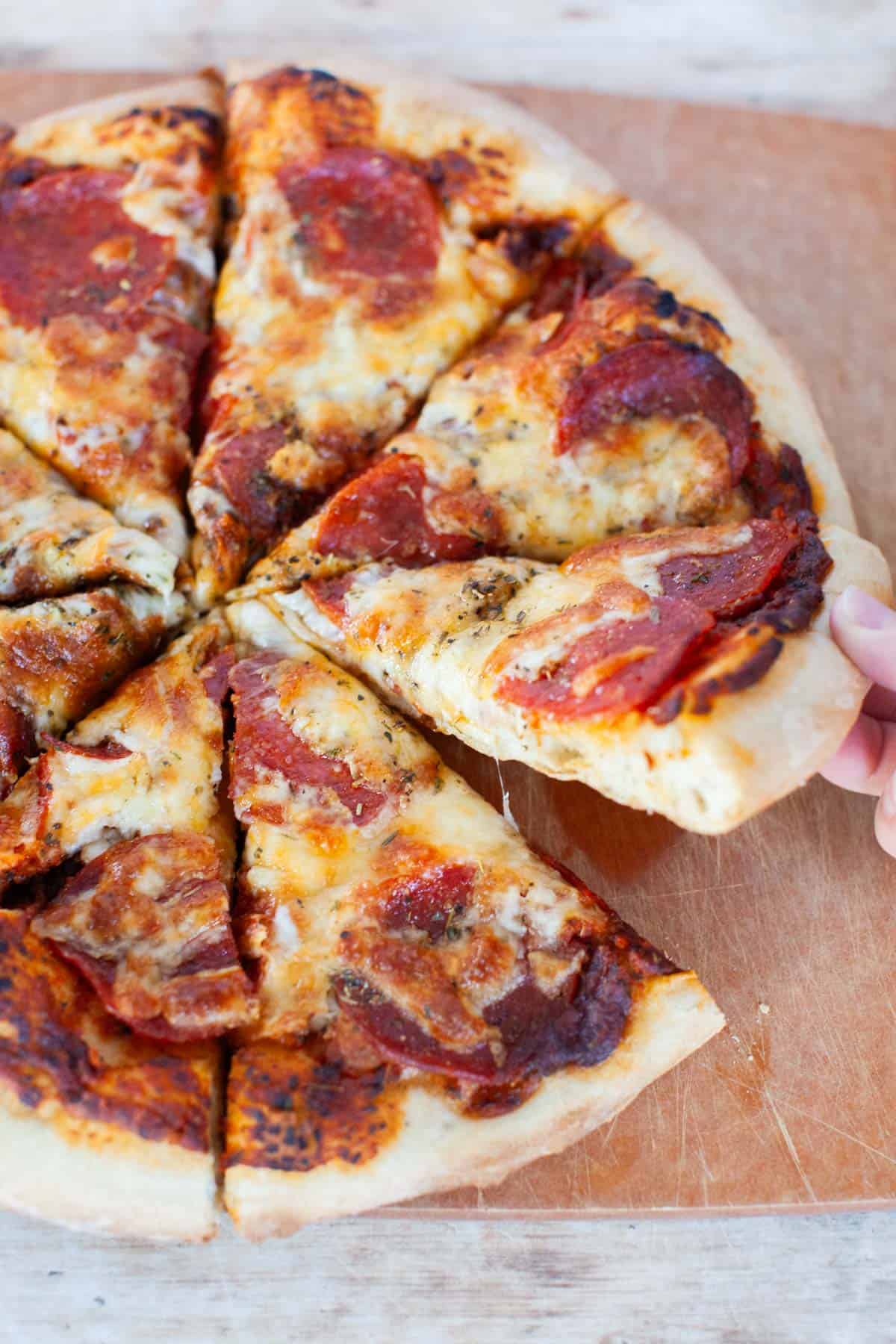 Grilled pizza on a cutting board cut into slices.