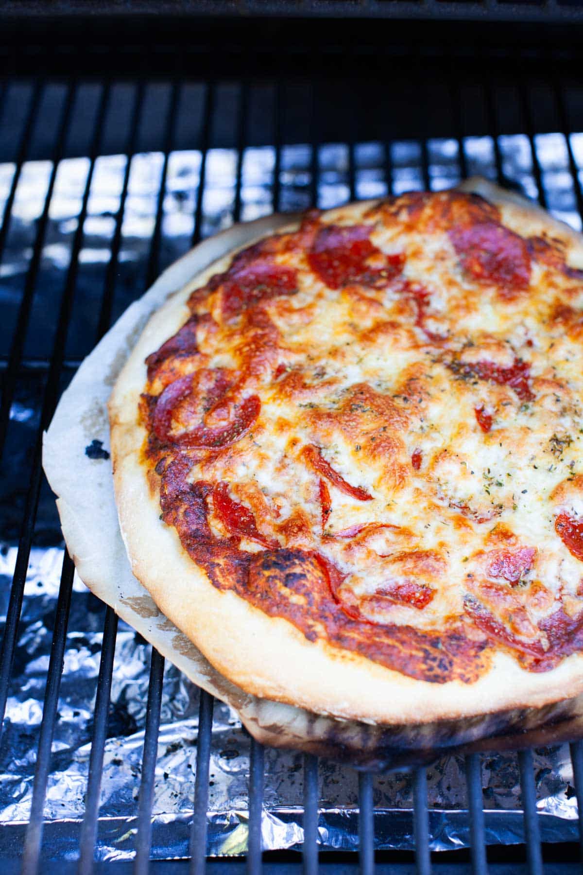 Grilled pizza fully cooked on a grill.