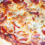 Overhead photo of Smoked Pizza with pepperoni and cheese on a grill.