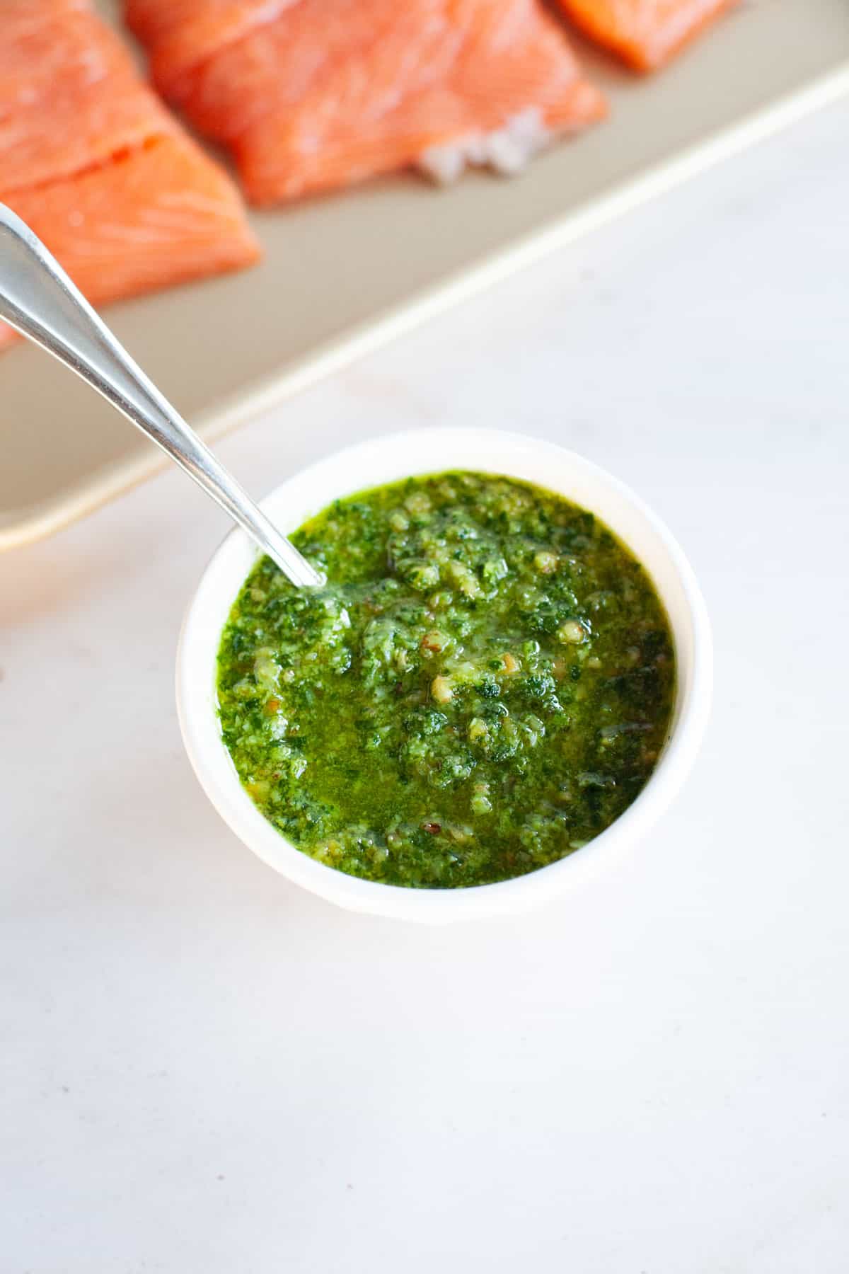 Small white bowl of pesto with a spoon.