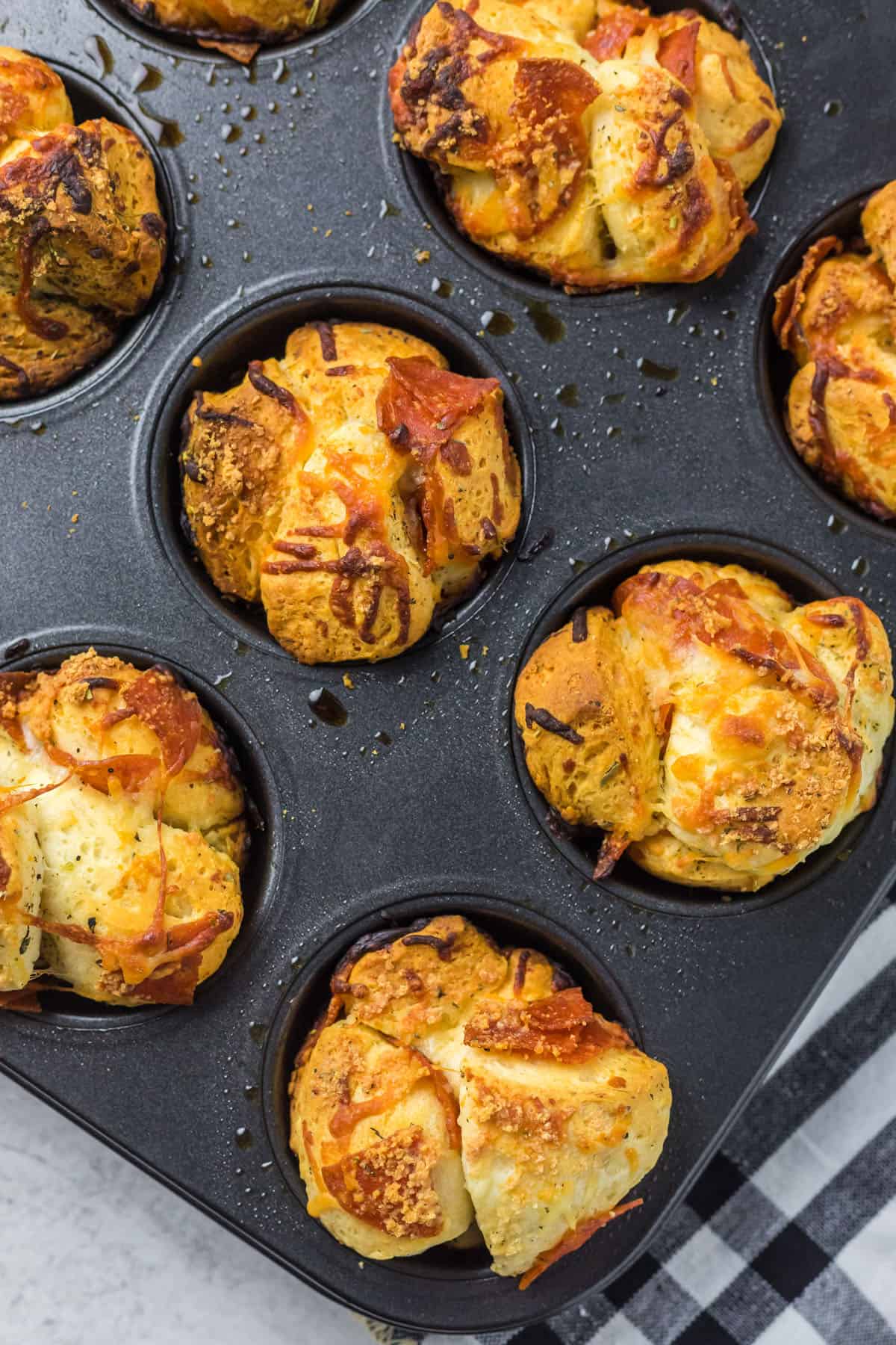Close up photo of fully cooked pizza muffins in a muffin tin.