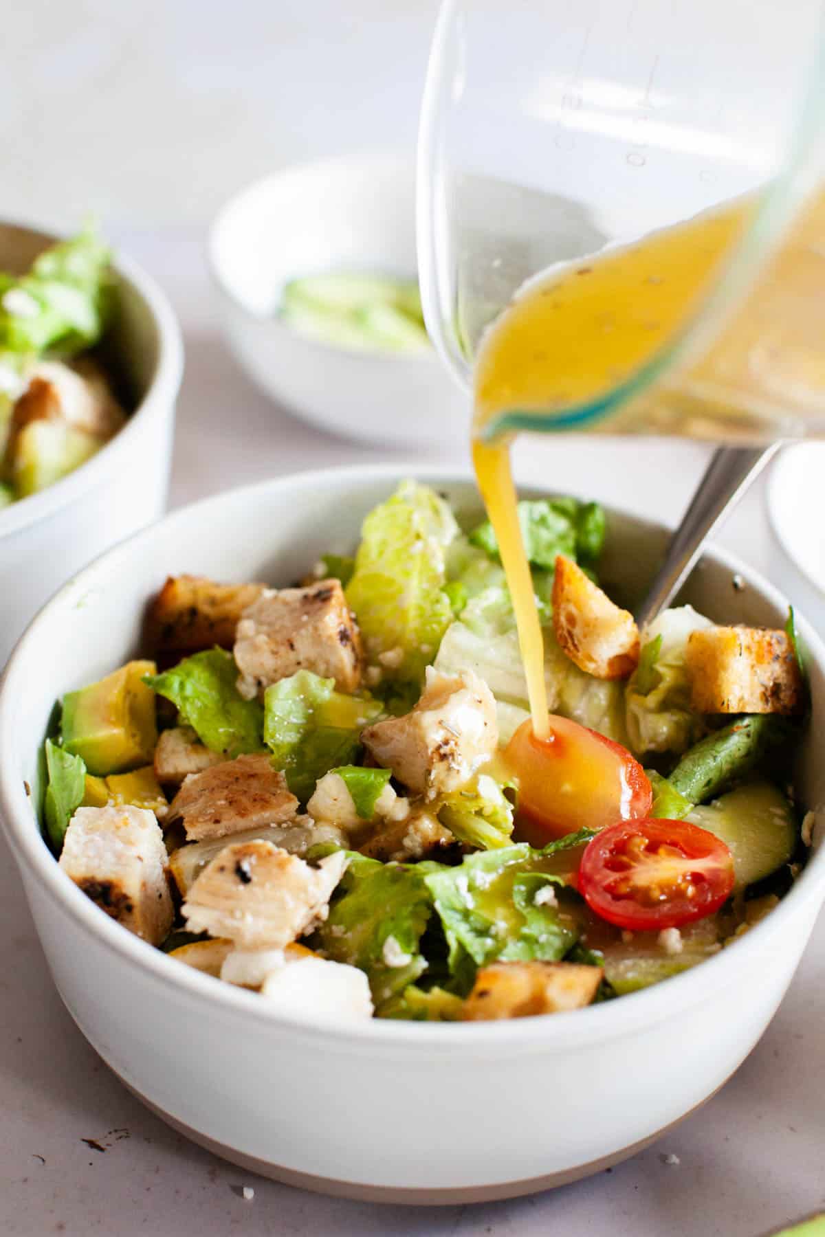 Honey vinaigrette being poured on grilled chicken salad.