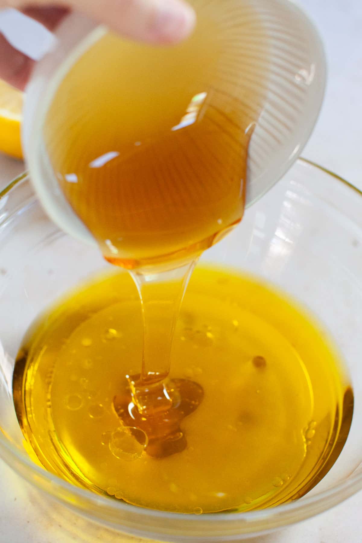 Honey being poured into a bowl with apple cider vinegar and lemon juice.