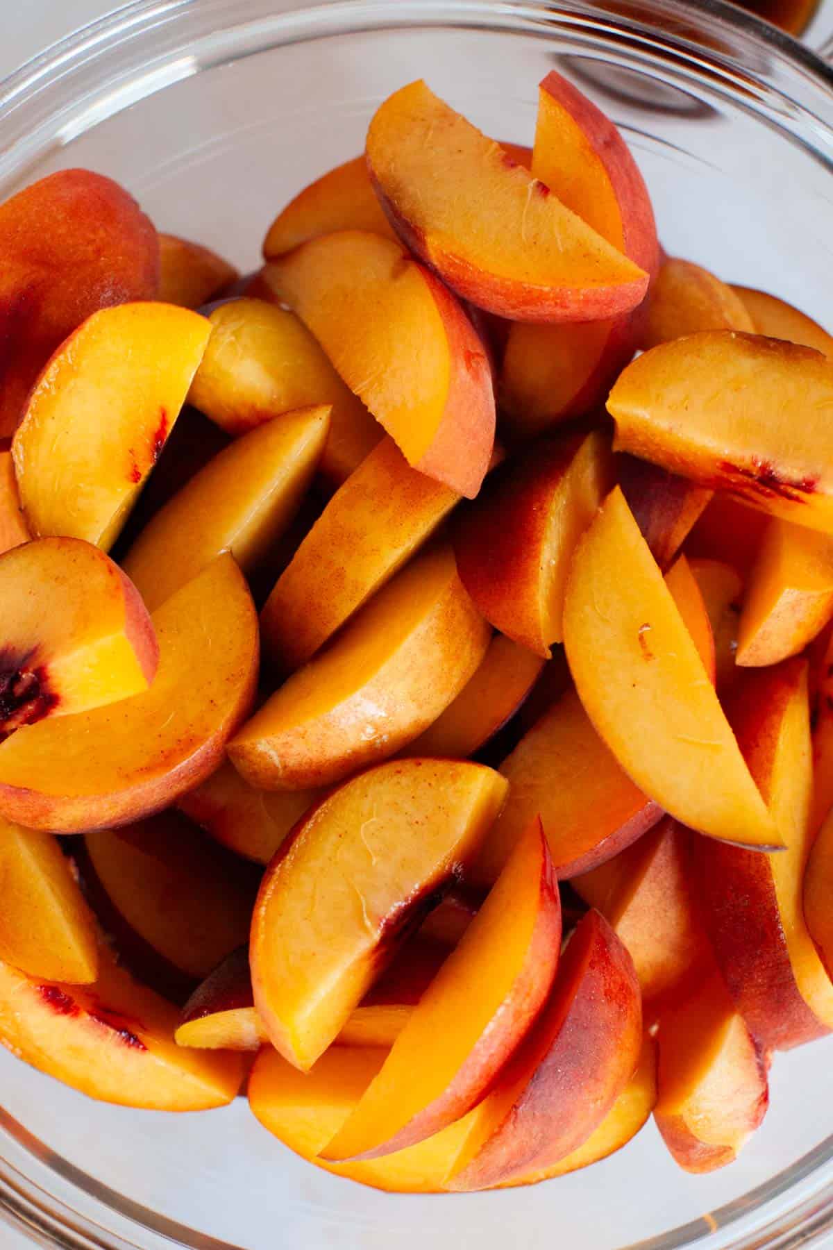 A glass bowl of fresh peaches.
