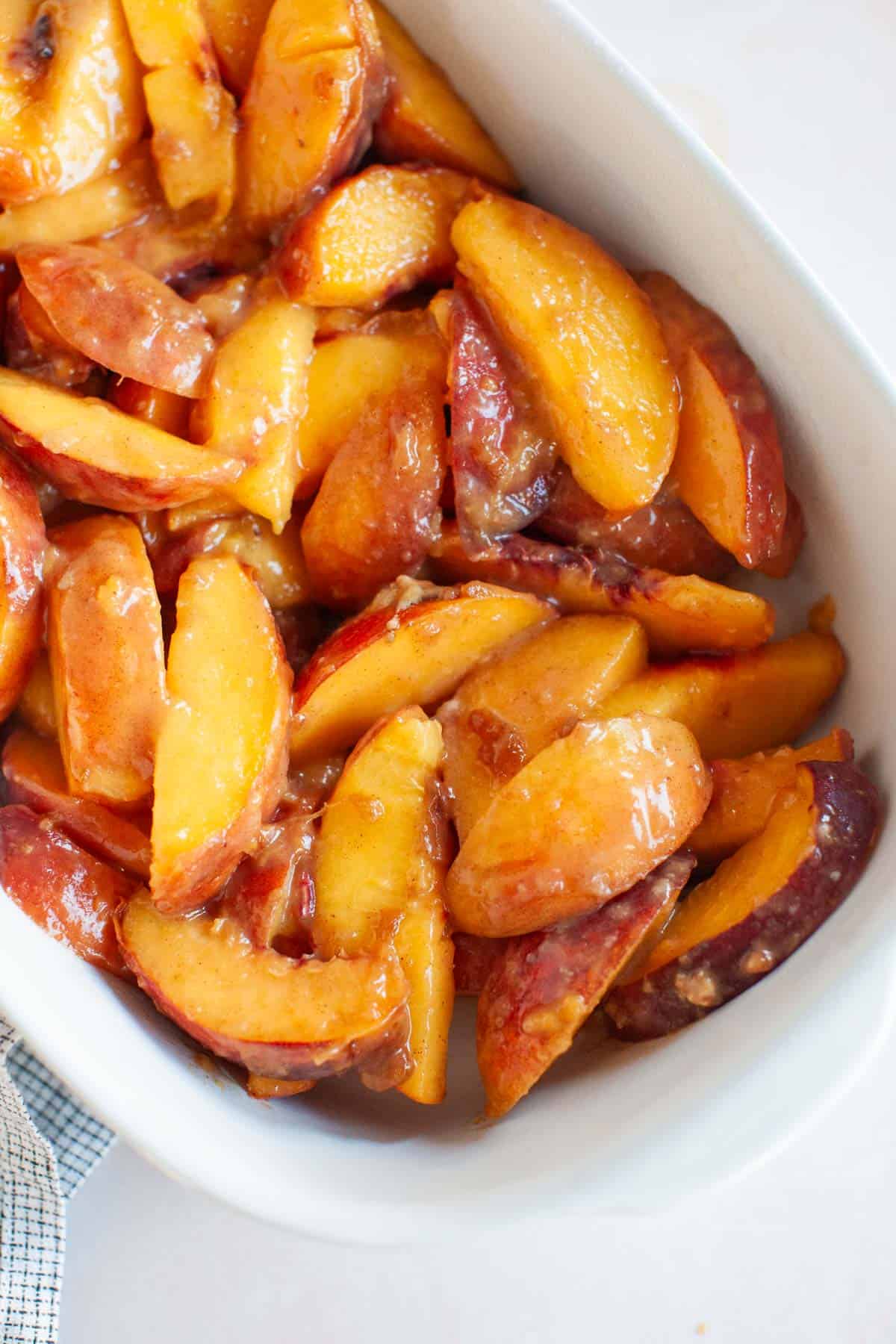 Warmed peaches in a white serving dish.