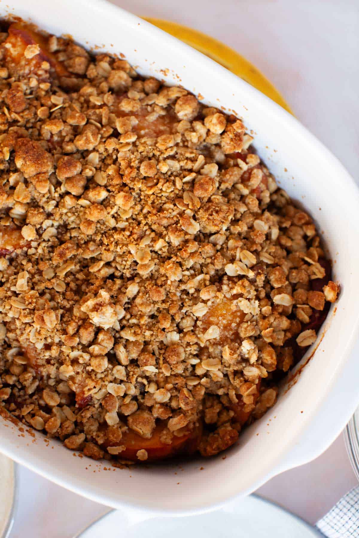 Peach crisp in a white serving dish.