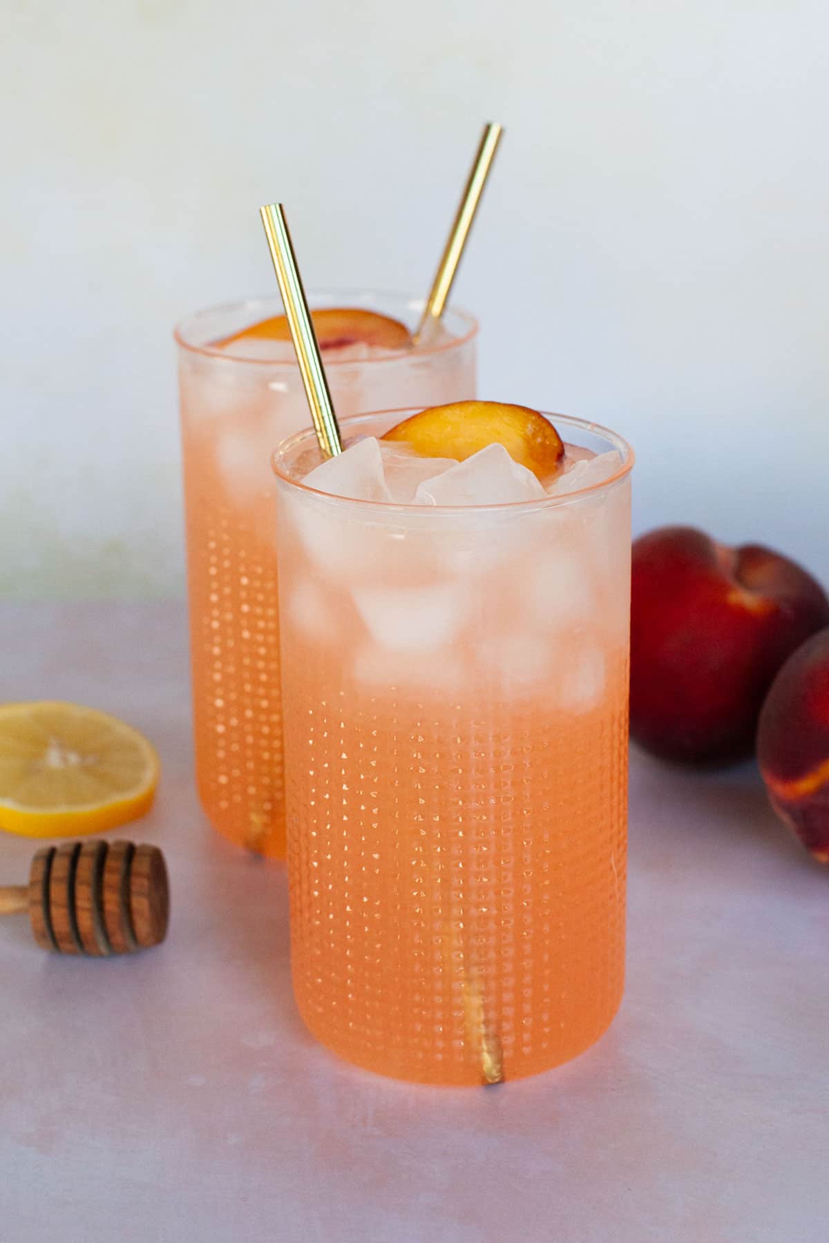 Tall glasses of peach lemonade with stainless steel straws.