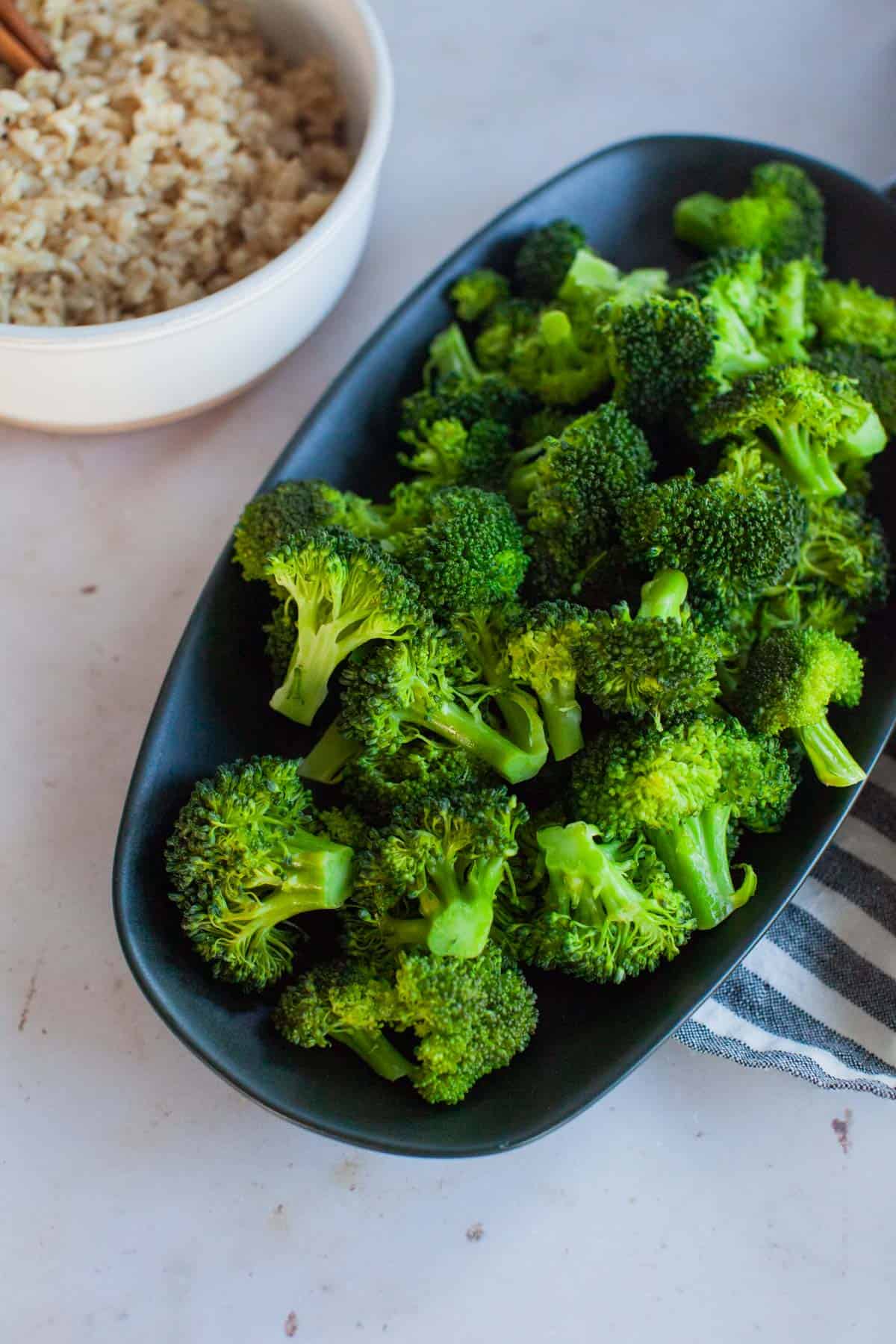 Steamed broccoli in a curved rectangular serving dish.