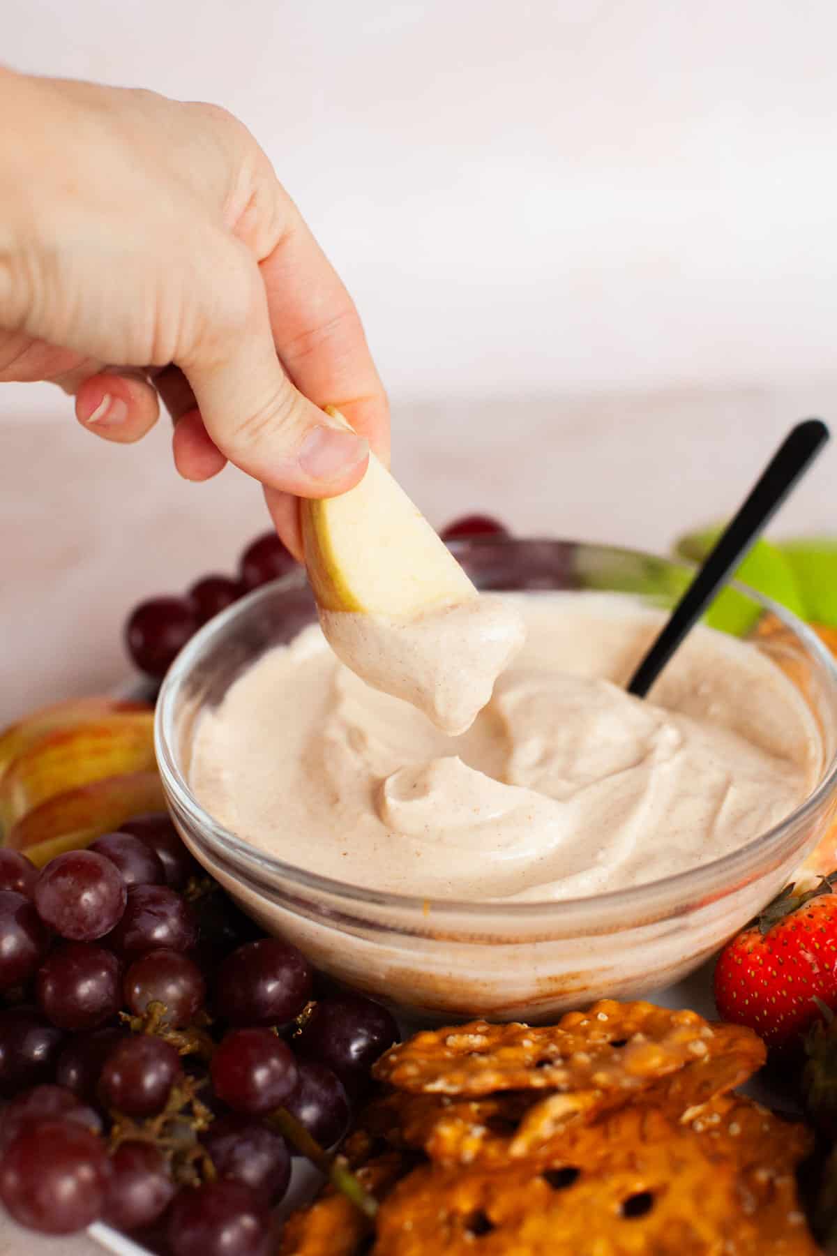 A gala apple being dipped into the fruit dip.