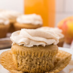 An unwrapped apple spice cupcake with cinnamon frosting on a plate.