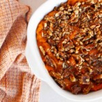 Sweet potato casserole with pecans in a white dish.