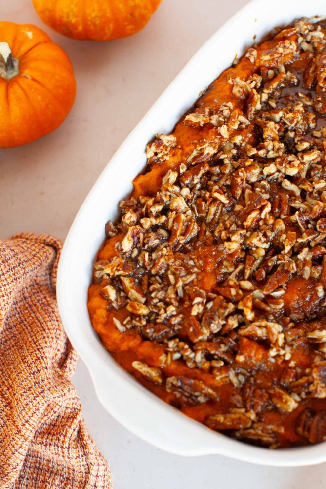 Sweet potato casserole with pecans in a white dish.