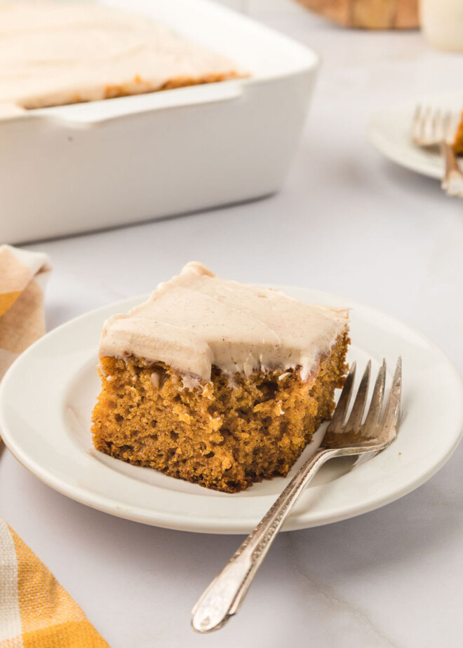 Maple cream cheese frosting on a slice of pumpkin cake with a bite taken out of it.