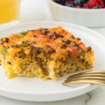 Breakfast casserole on a plate with berries and a fork.