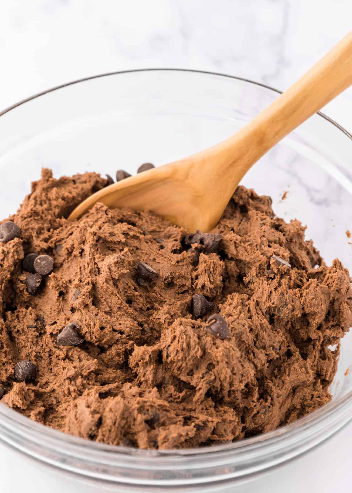 Double chocolate chip cookie dough in a bowl with a wooden spoon.