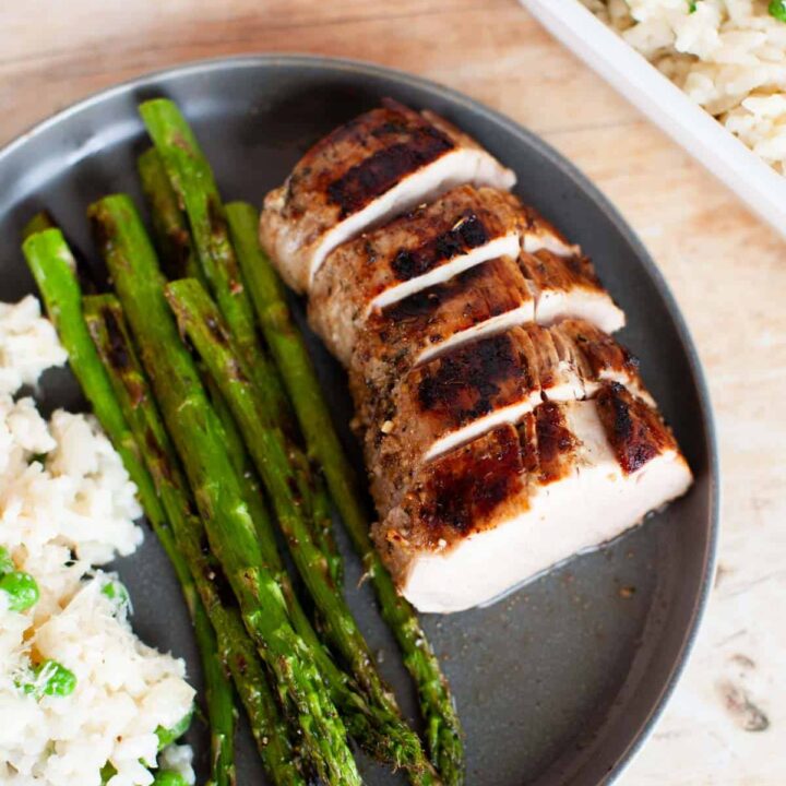 Marinated pork tenderloins with asparagus and risotto on a plate.