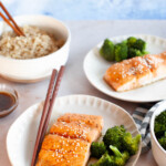 Two plates of teriyaki-glazed salmon with broccoli.