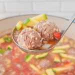 A spoon full Mexican meatballs and zucchini.