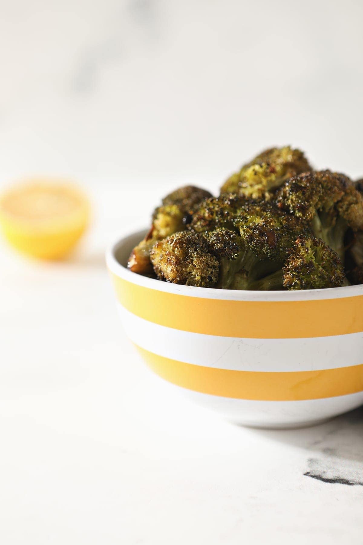 Roasted broccoli in a yellow and white bowl.