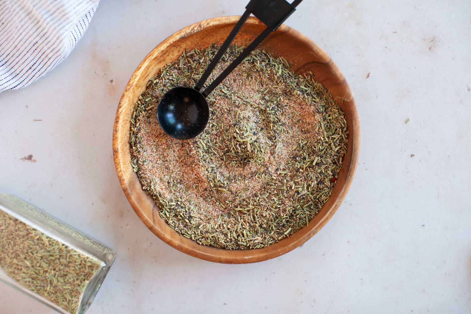 A bowl of herbs and spices on a table.