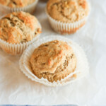 Four banana muffins on a white sheet of paper.