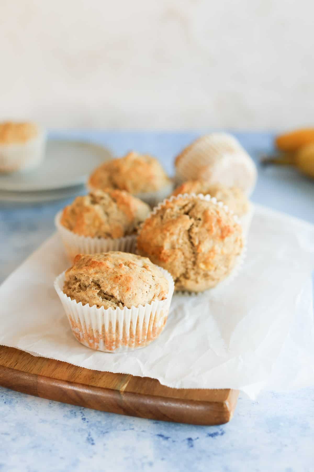 A group of banana bread muffins on a parchment paper-lined cutting board.