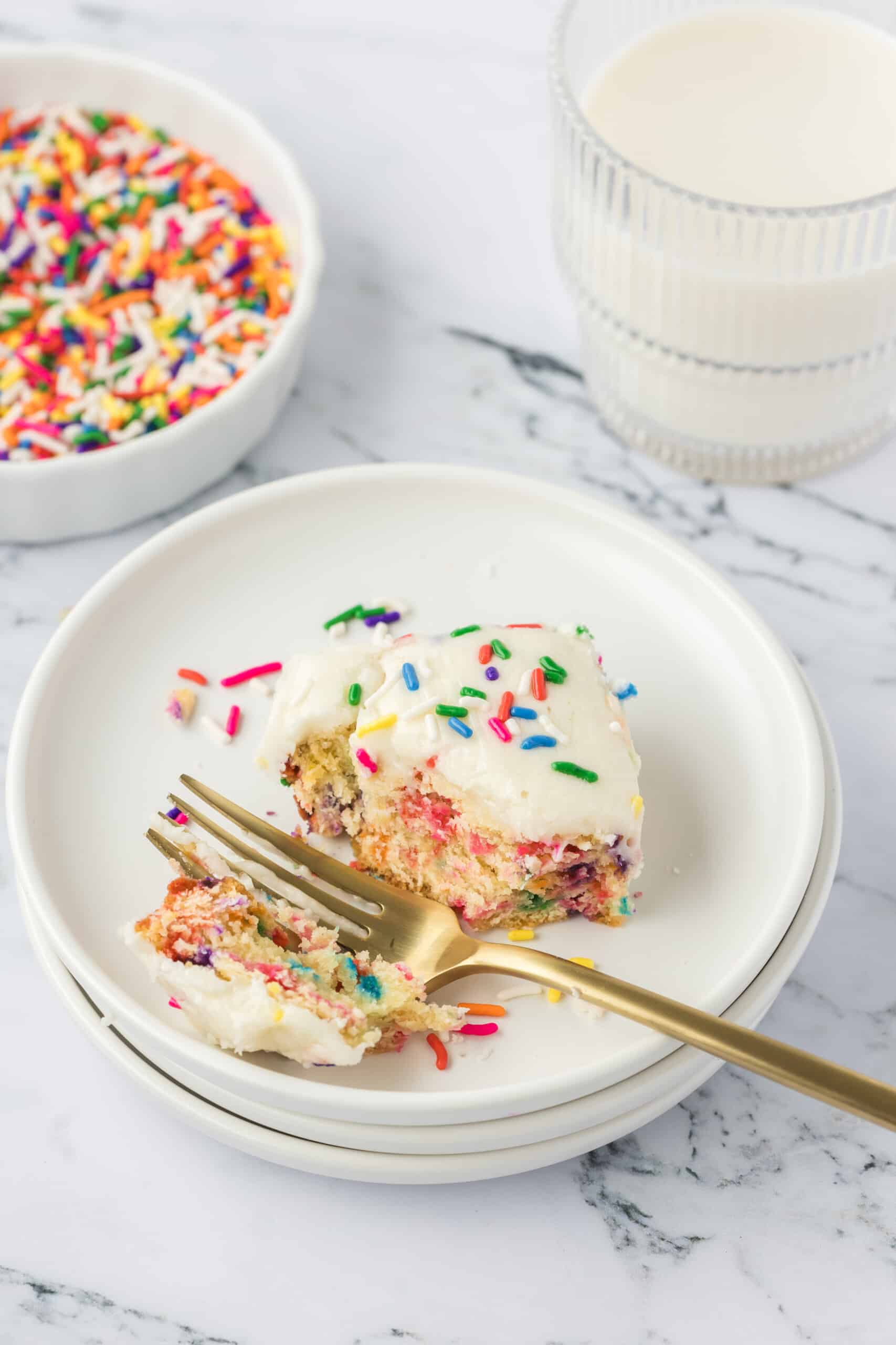 A slice of funfetti sugar cookie bar with sprinkles on a plate.