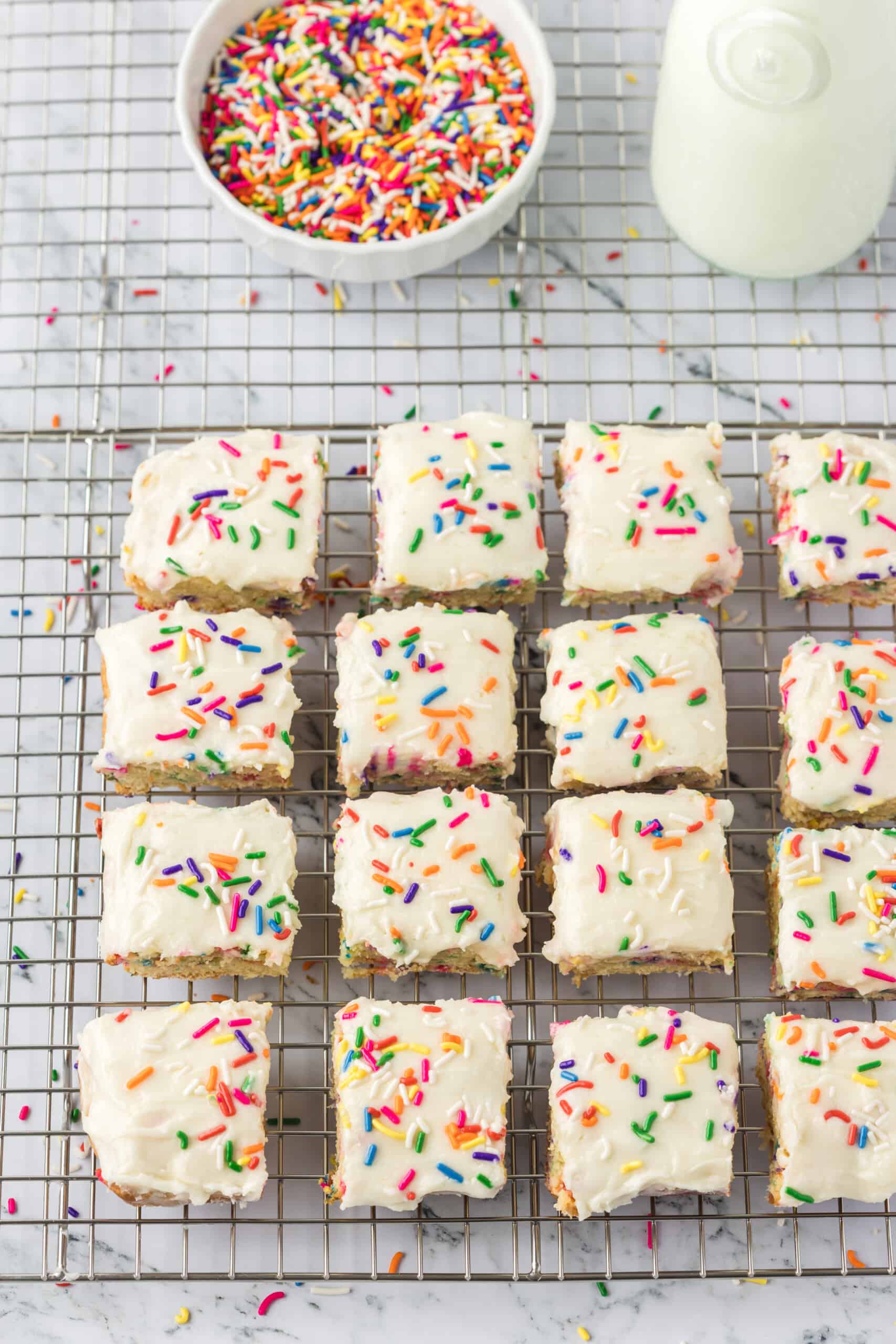 Funfetti sugar cookie bars with sprinkles on a cooling rack.