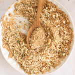 Italian breadcrumbs on a plate with a wooden spoon.