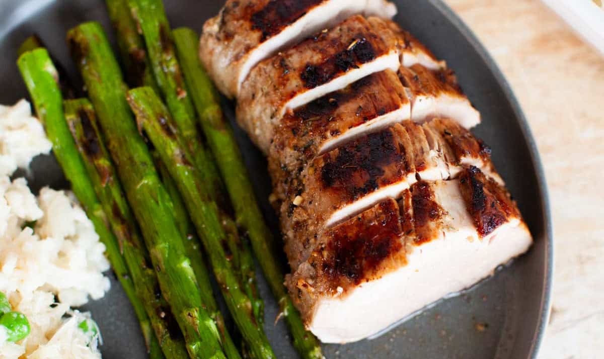 Grilled pork tenderloin and asparagus on a plate.