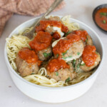 Turkey spinach meatballs topped with marinara sauce on a bed of spaghetti.