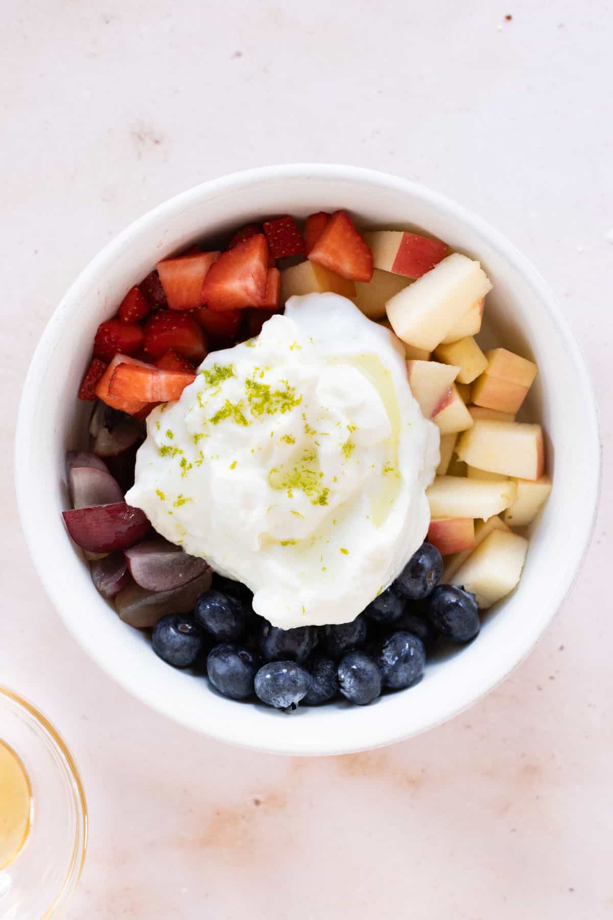 A bowl full of fruit and yogurt with lime zest.