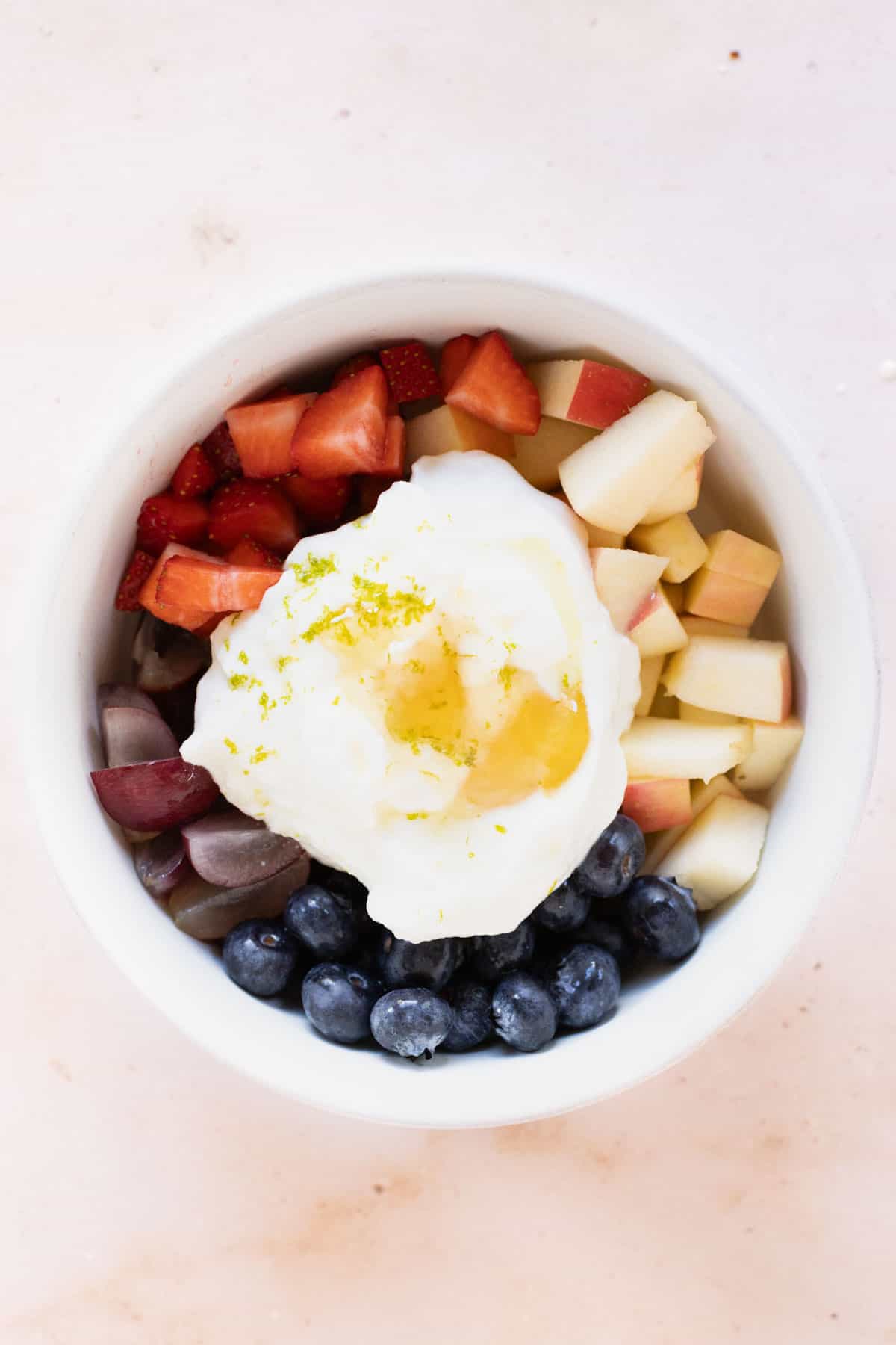 A bowl filled with fruit topped with yogurt and lime zest.