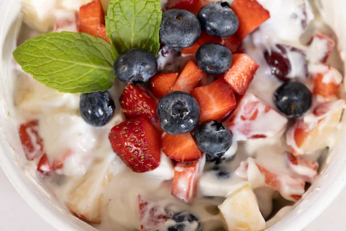 Creamy fruit salad in a white bowl.