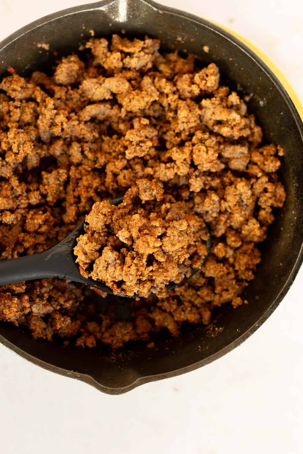 A bowl of easy taco meat with a spoon.