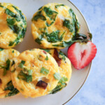 A plate of egg bites with a sliced strawberry.