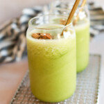 Kale smoothies in glass jars with metal straws.